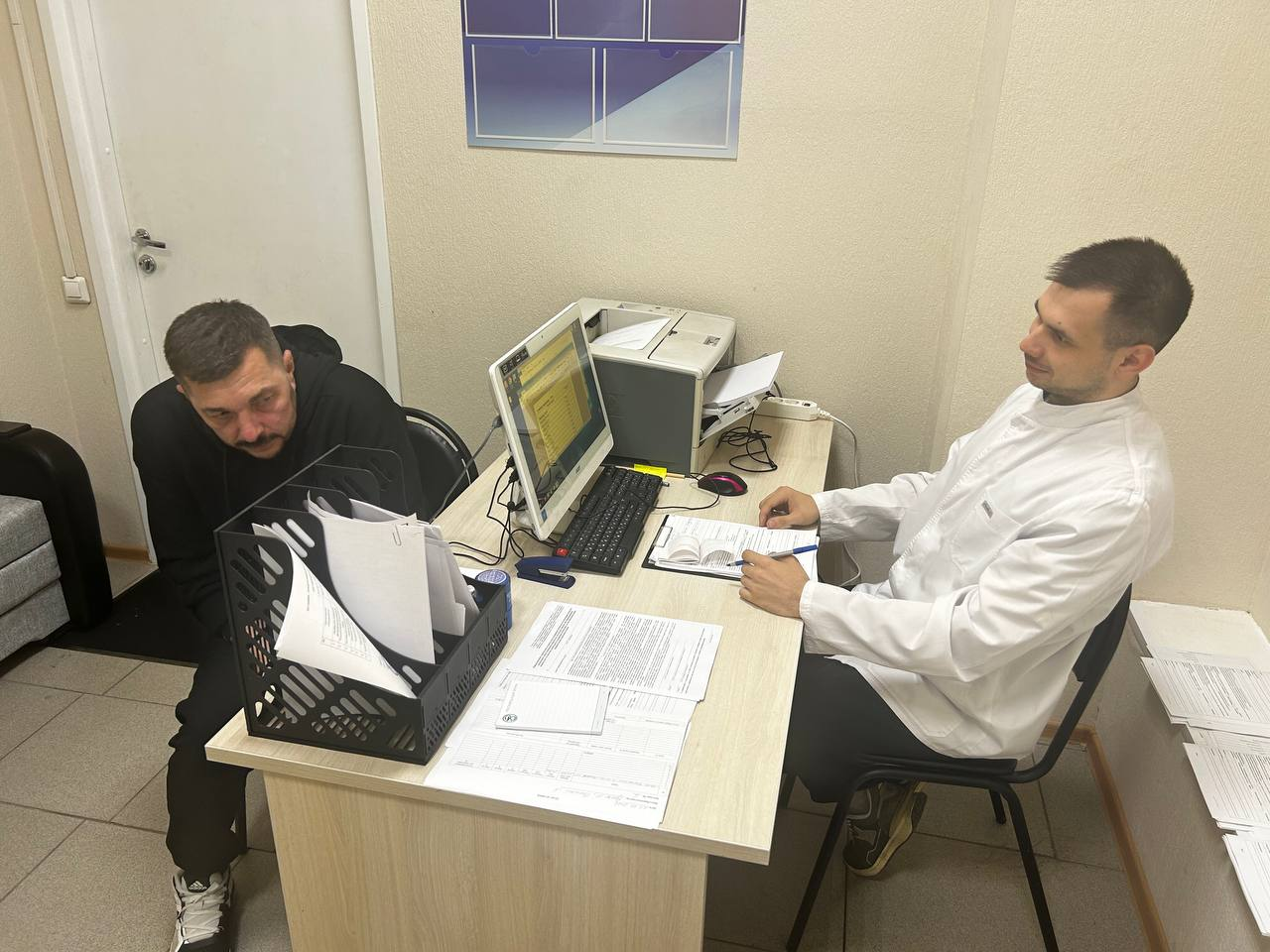Врач оформляет документы вместе с пациентом на приёме в клинике