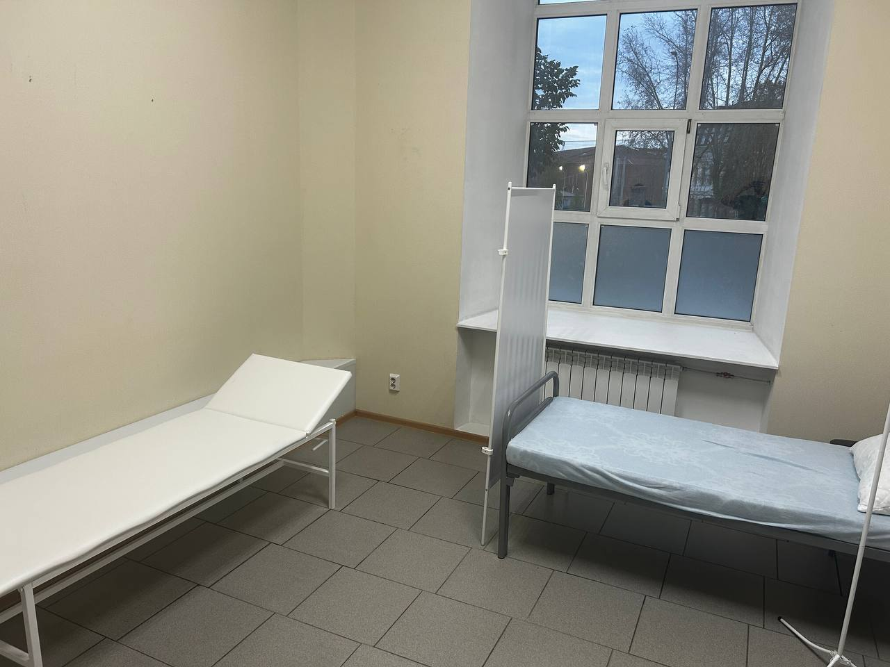 Палата с кушеткой и больничной кроватью, разделёнными ширмой у окна